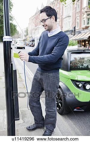 Man charging electric car on street View Large Photo Image Stock Photograph - Man charging electric car on street. Fotosearch