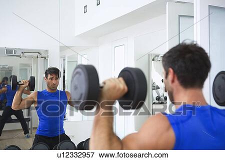 Stock Photo - Man lifting weights in gym. Fotosearch