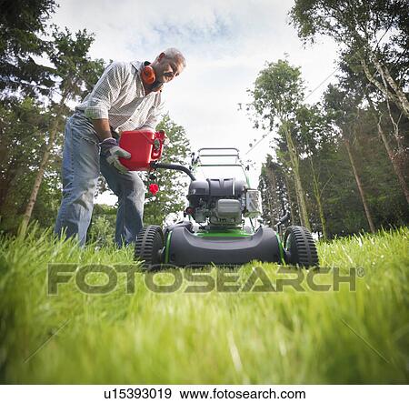 Man pouring gas into lawn mower View Large Photo Image Stock Photo - Man pouring gas into lawn mower. Fotosearch