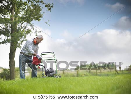 Stock Photography - Man pouring gas into lawn mower. Fotosearch