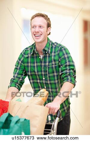 Stock Image - Man pushing shopping cart in mall. Fotosearch