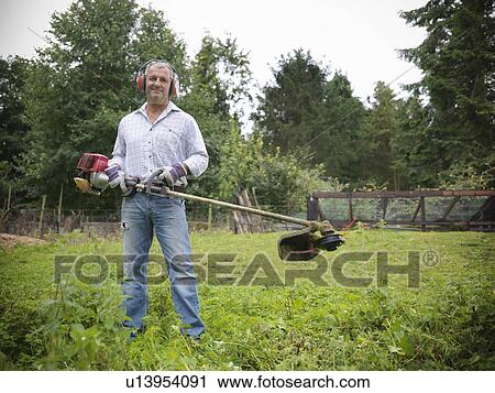 Man trimming weeds in garden View Large Photo Image Stock Image - Man trimming weeds in garden. Fotosearch