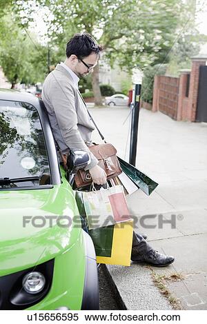 Man with shopping bags leaning on car View Large Photo Image Stock Photography - Man with shopping bags leaning on car. Fotosearch