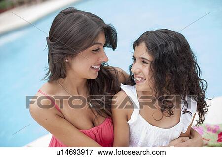 Mother and daughter sitting by pool View Large Photo Image Stock Photo - Mother and daughter sitting by pool. Fotosearch
