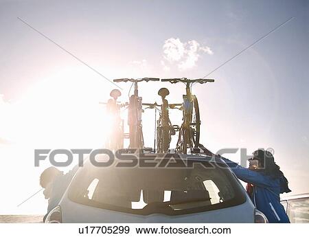 Stock Photo - Mother and son tying bicycles on car. Fotosearch