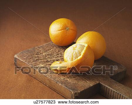 Stock Image - Peeling orange on wooden board. Fotosearch