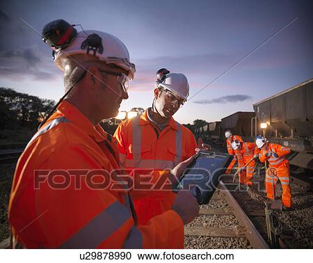 Stock Image - Railway workers using tablet computer. Fotosearch