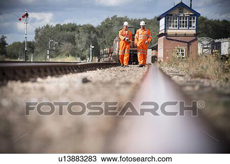 Railway workers walking on train tracks View Large Photo Image Stock Image - Railway workers walking on train tracks. Fotosearch