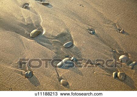 Stock Image - Sand formations around rocks on beach. Fotosearch