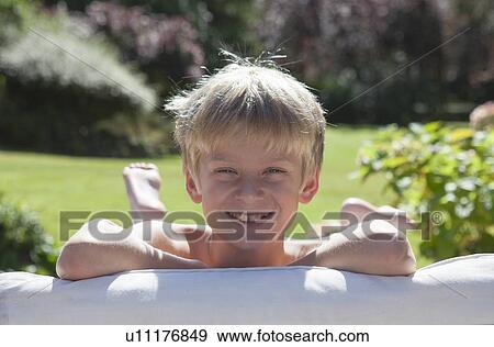 Smiling boy laying on sofa outdoors View Large Photo Image Stock Photo - Smiling boy laying on sofa outdoors. Fotosearch