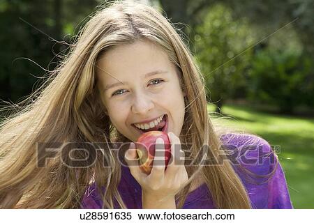 Stock Photography - Smiling girl eating apple in park. Fotosearch