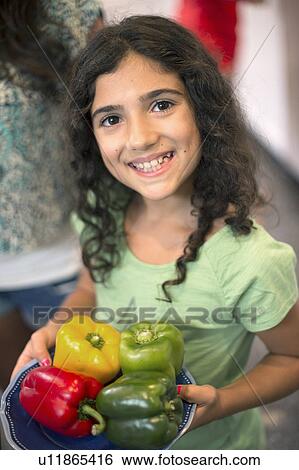 Stock Photograph - Smiling girl holding bowl of peppers. Fotosearch