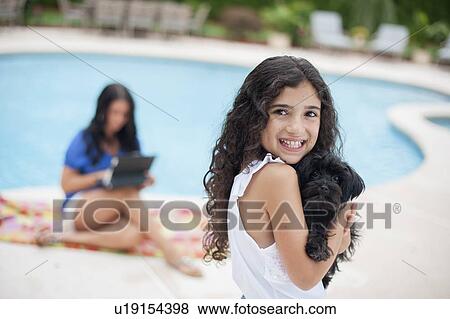 Stock Photo - Smiling girl holding puppy by pool. Fotosearch
