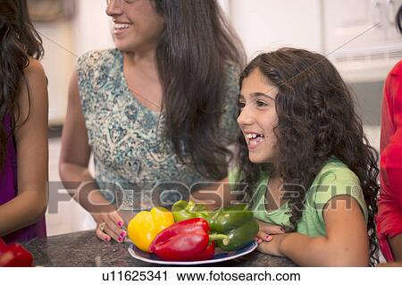 Stock Image - Smiling girl with family in kitchen. Fotosearch