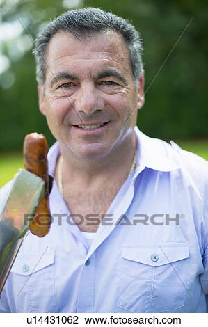 Smiling man grilling hot dog outdoors View Large Photo Image Stock Image - Smiling man grilling hot dog outdoors. Fotosearch