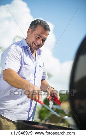 Stock Photo - Smiling man grilling outdoors. Fotosearch