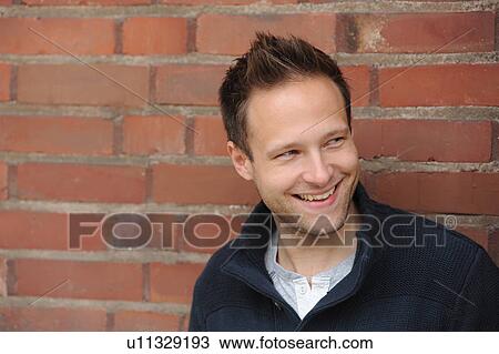 Smiling man leaning against brick wall View Large Photo Image Stock Image - Smiling man leaning against brick wall. Fotosearch