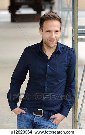 Picture - Smiling man leaning against wall. Fotosearch