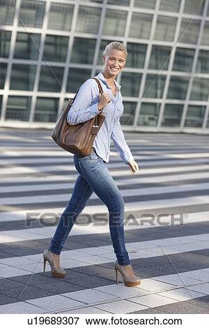 Stock Photo - Smiling woman crossing city street. Fotosearch