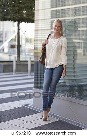 Smiling woman leaning against building View Large Photo Image Stock Image - Smiling woman leaning against building. Fotosearch