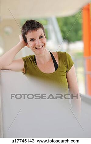Stock Image - Smiling woman leaning on bar. Fotosearch