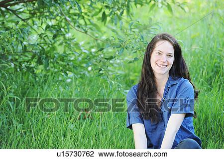 Smiling woman sitting in grass View Large Photo Image Stock Image - Smiling woman sitting in grass. Fotosearch