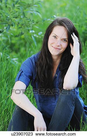 Smiling woman sitting in grass View Large Photo Image Stock Image - Smiling woman sitting in grass. Fotosearch