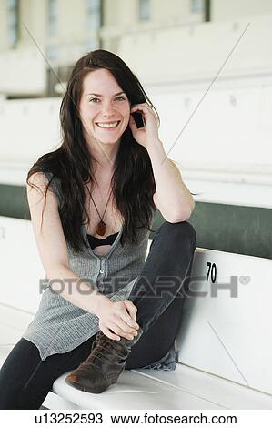 Stock Image - Smiling woman sitting on bench. Fotosearch