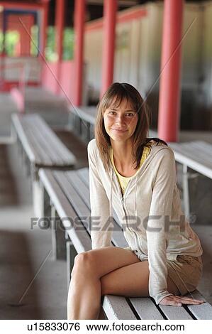 Stock Photograph - Smiling woman sitting on bench. Fotosearch