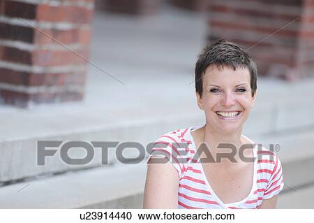 Smiling woman sitting on city street View Large Photo Image Stock Image - Smiling woman sitting on city street. Fotosearch
