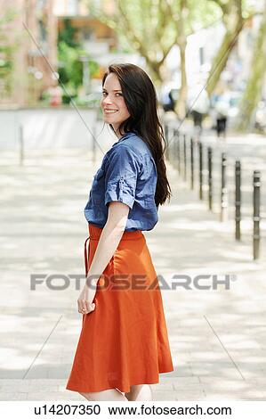 Stock Image - Smiling woman standing on city street. Fotosearch