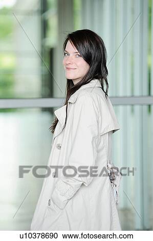 Stock Image - Smiling woman wearing trench coat. Fotosearch