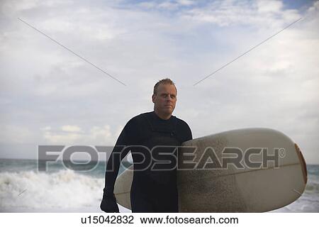 Surfer carrying board on beach View Large Photo Image Stock Image - Surfer carrying board on beach. Fotosearch