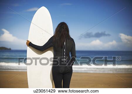 Surfer holding board on beach View Large Photo Image Stock Photo - Surfer holding board on beach. Fotosearch