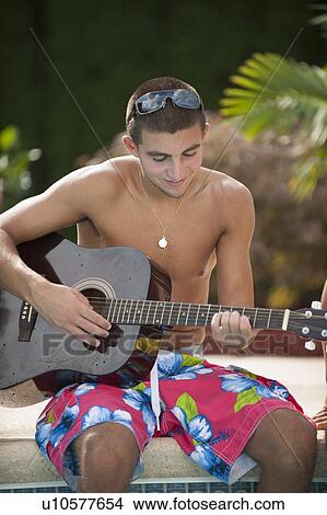 Teenage boy playing guitar by pool View Large Photo Image Picture - Teenage boy playing guitar by pool. Fotosearch
