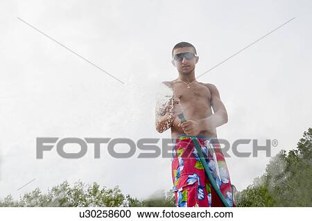 Teenage boy spraying water hose View Large Photo Image Stock Image - Teenage boy spraying water hose. Fotosearch