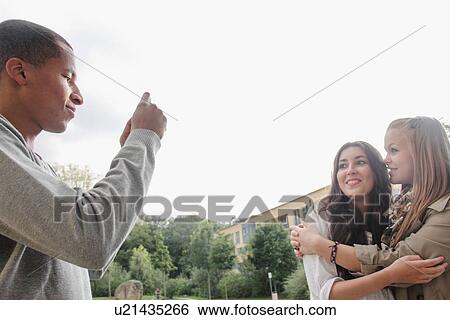 Stock Photograph - Teenage boy taking pictures of friends. Fotosearch