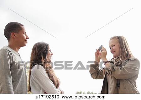 Stock Image - Teenage girl taking pictures of friends. Fotosearch