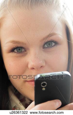 Stock Image - Teenage girl using cell phone outdoors. Fotosearch