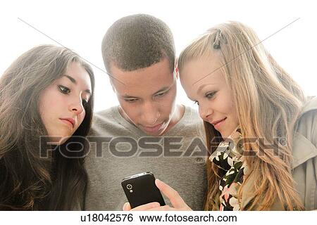 Stock Photograph - Teenagers using cell phone outdoors. Fotosearch