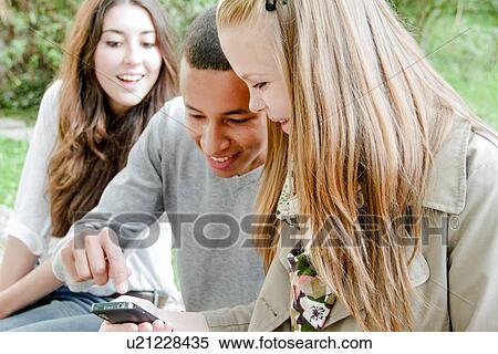 Stock Photography - Teenagers using cell phone outdoors. Fotosearch