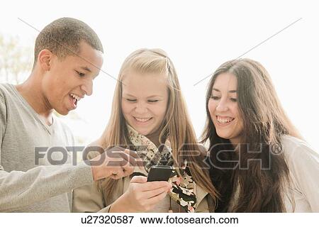Teenagers using cell phone together View Large Photo Image Stock Photo - Teenagers using cell phone together. Fotosearch