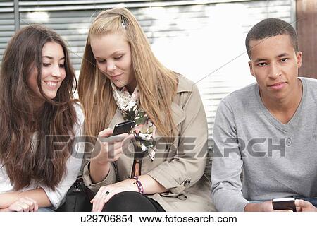 Teenagers using cell phones outdoors View Large Photo Image Picture - Teenagers using cell phones outdoors. Fotosearch