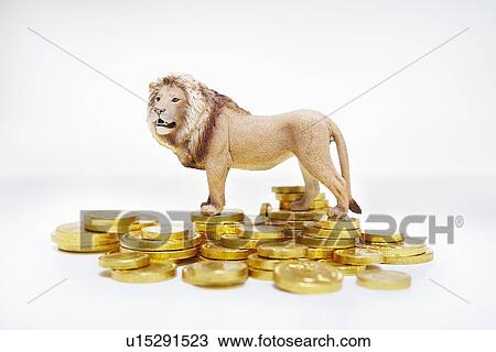 Stock Image - Toy lion on stacks of gold coins. Fotosearch