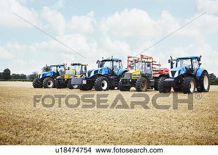 Picture - Tractors parked in tilled crop field. Fotosearch