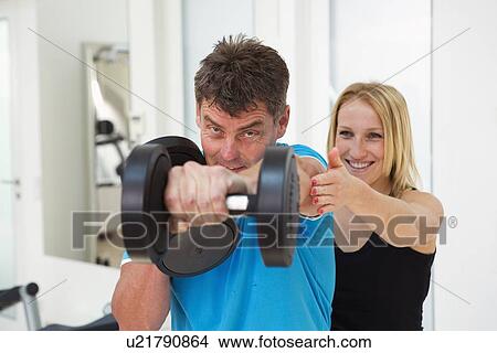 Trainer adjusting man’s form in gym View Large Photo Image Picture - Trainer adjusting man’s form in gym. Fotosearch