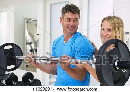 Trainer adjusting man’s form in gym View Large Photo Image Stock Photo - Trainer adjusting man’s form in gym. Fotosearch