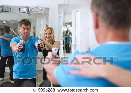 Trainer adjusting man’s form in gym View Large Photo Image Stock Photo - Trainer adjusting man’s form in gym. Fotosearch