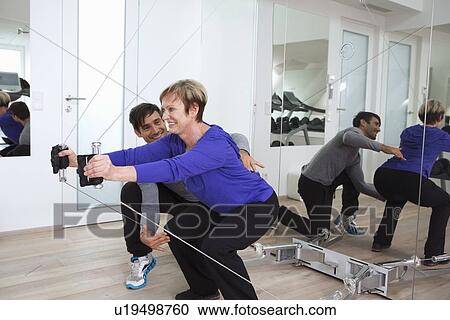Trainer adjusting woman’s form in gym View Large Photo Image Stock Image - Trainer adjusting woman’s form in gym. Fotosearch