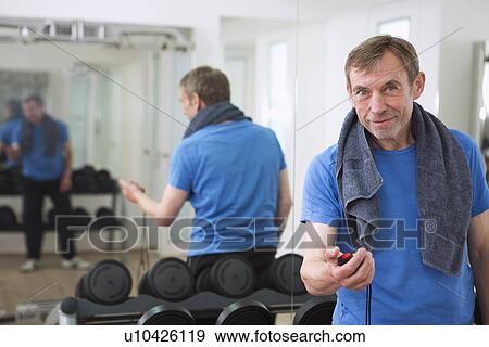 Stock Photo - Trainer holding stopwatch in gym. Fotosearch